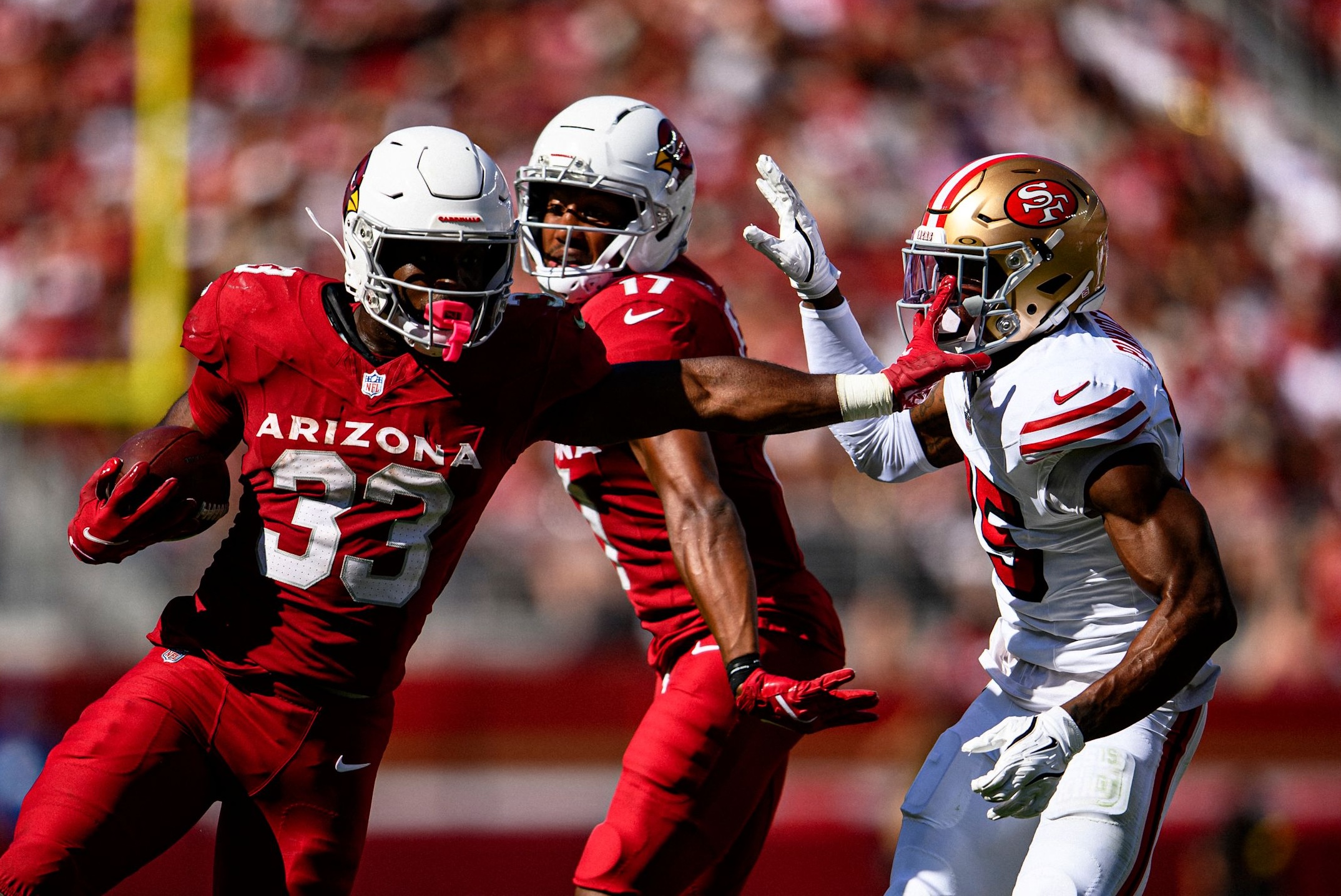 Cardinals running back Trey Benson (33) stiff arms a defender in a loss to the 49ers in Week 3 of the 2025 NFL season.